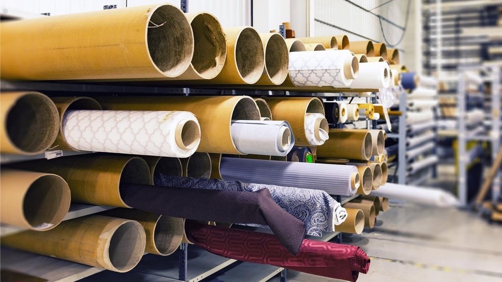 At Finde bæredygtige stoffer og vælge den rigtige produktionsmetode Mode designer gennemgår stofruller og produktionsmuligheder